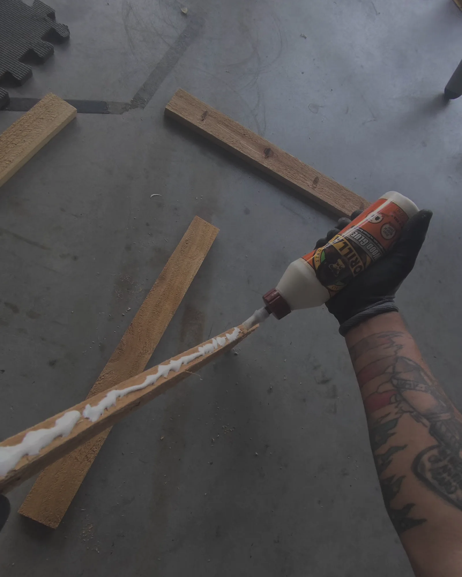 A bead of wood glue run along a narrow cedar strip held in a gloved hand