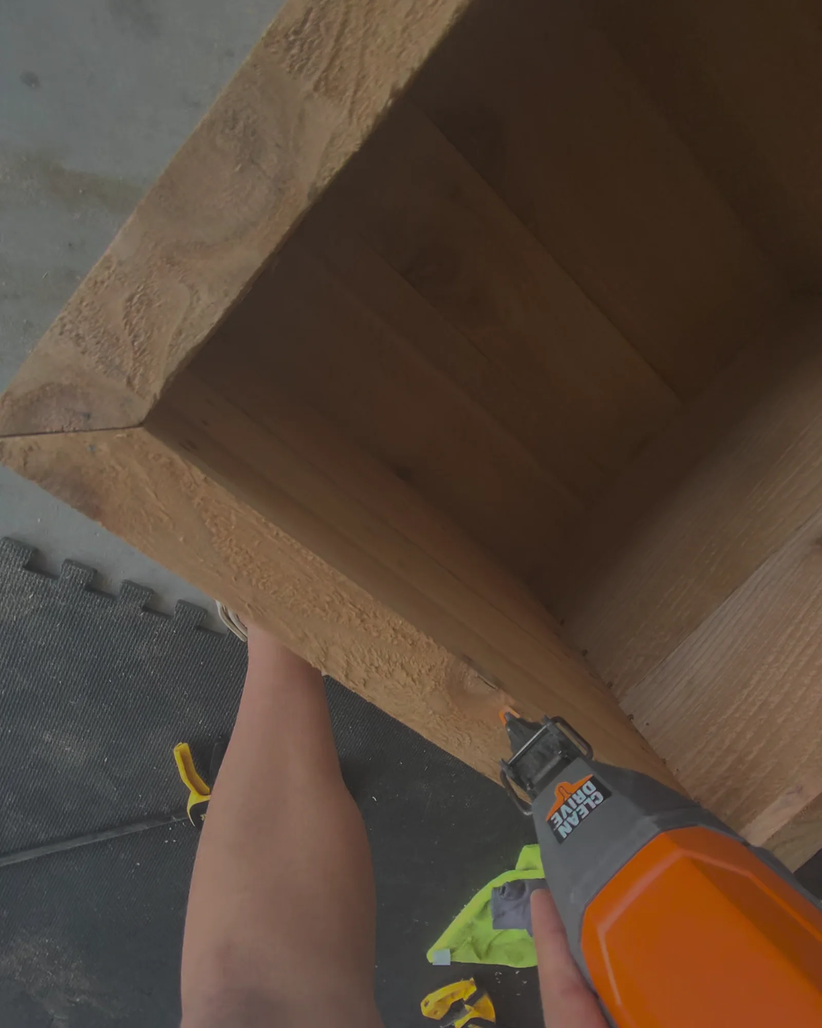 A brad nailer seating the corner of the planter box, a hand steadying the side